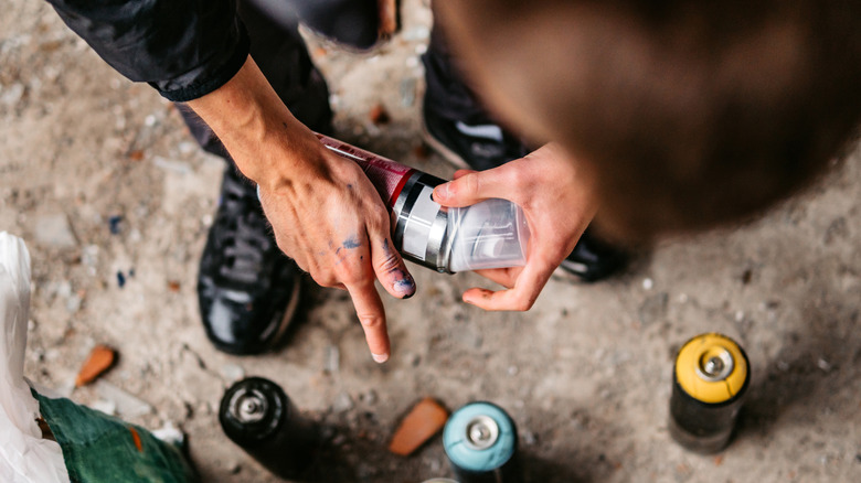 A person removing the lid from a spray paint can