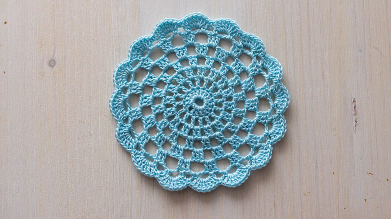 A light blue doily on an unfinished wood backdrop.