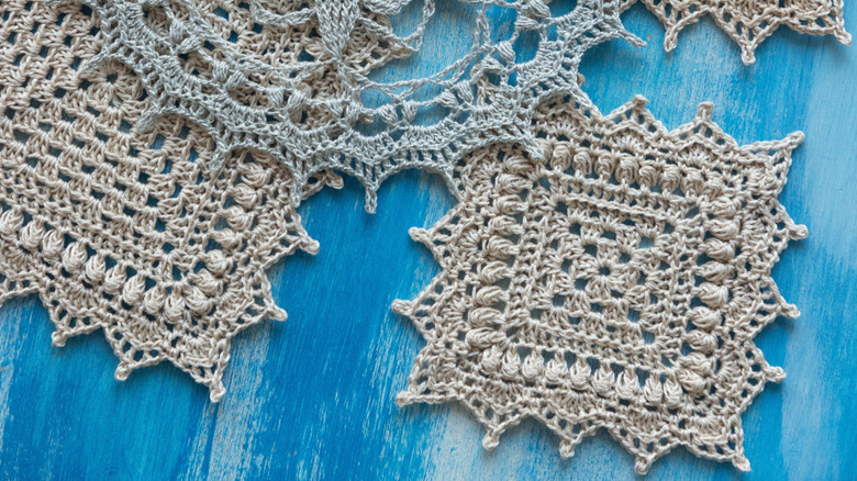 Vintage knit blue, red, and beige colored doilies on a blue backdrop.