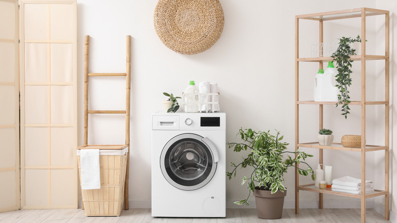 A washer and dryer in a laundry room with a pile of clothes in front of them