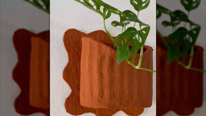 A wicker basket has been remade to look like a terracotta pot wall hanging.