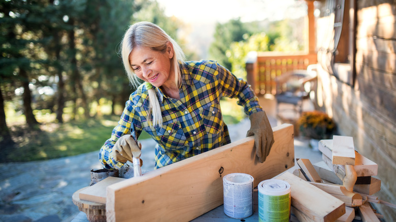 A woman painting a wooden plank outside