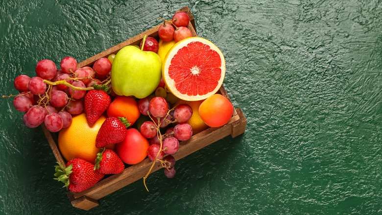 a fruit basket filled with grapes, apples, oranges, and strawberries