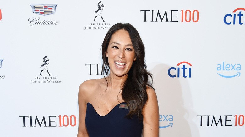 Joanna Gaines smiling at the camera, wearing a strapless navy dress