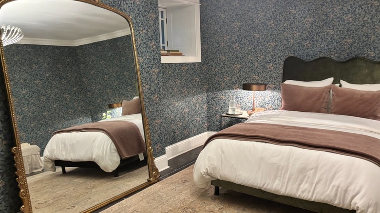 Castle bedroom with floral wallpaper and gold-framed mirror against the wall