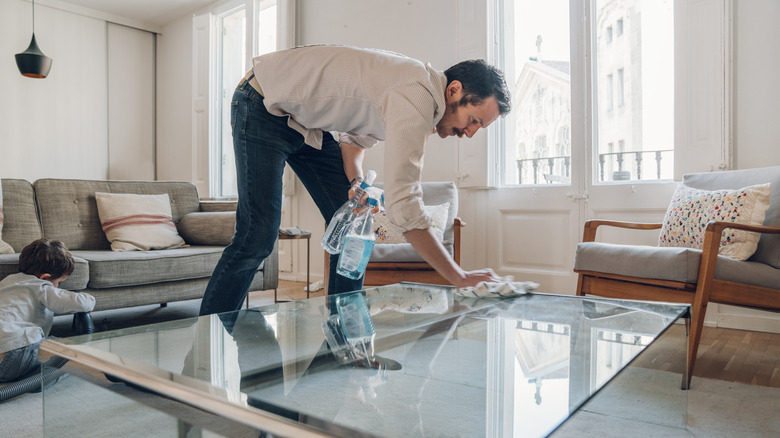 Man cleaning glass table