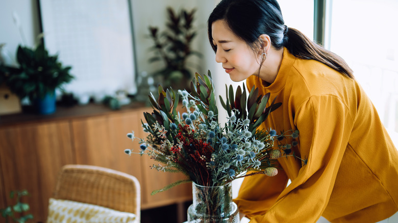 woman with vase of greens in home