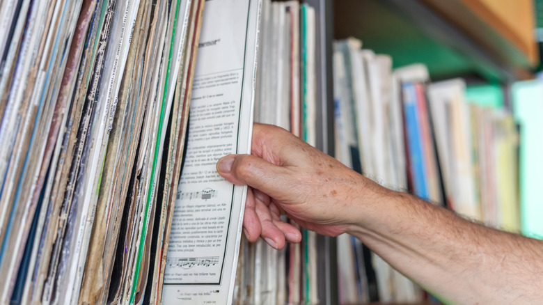 a person's hand pulling a vinyl record from a shelf