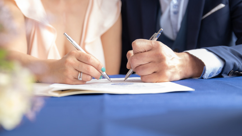 People signing marriage certificate