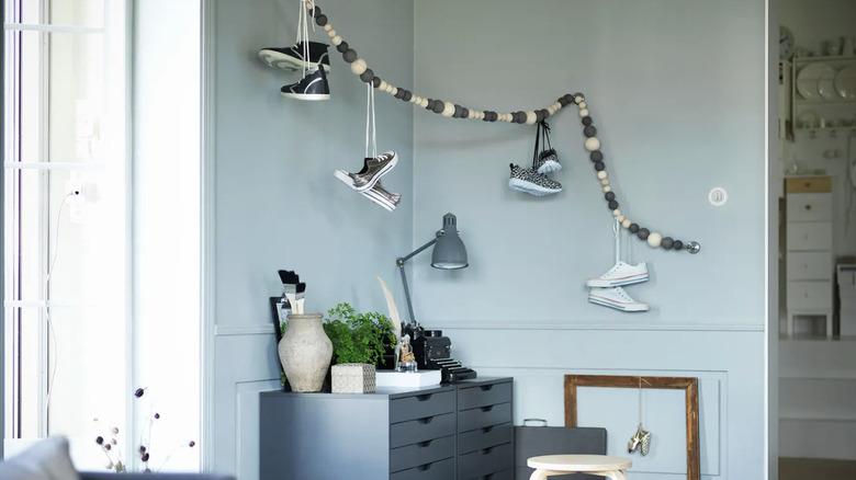 Sneakers hanging by their laces from a wire with wooden balls.