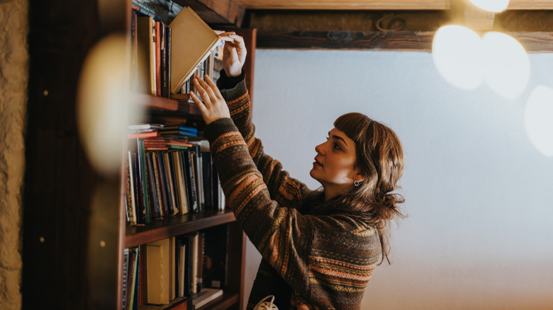 Someone pulling out a book from a bookshelf