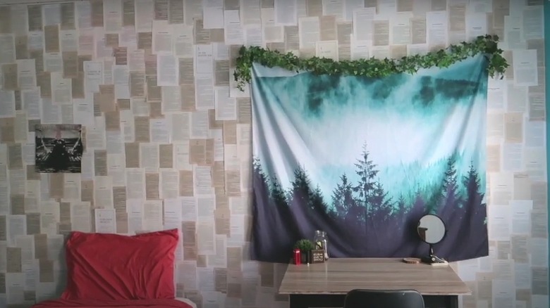Bedroom wall covered in book pages and tapestry