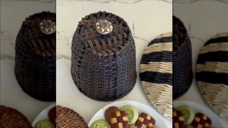 A finished DIY food cover created with a drawer pull and upcycled woven trash can sits on the counter.