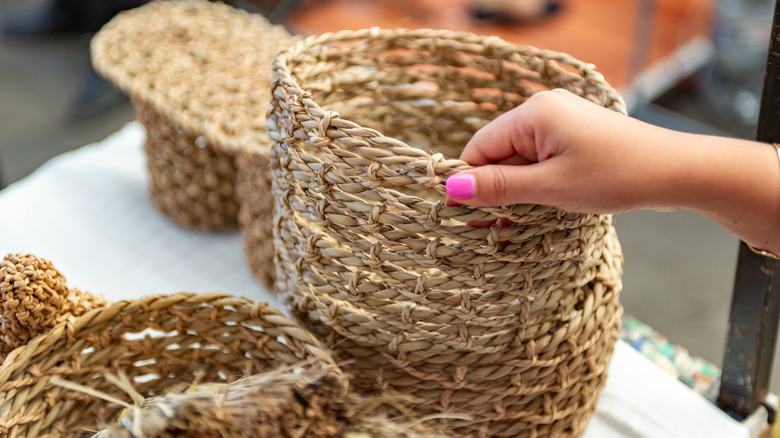 Woman examines a woven trash can to decide if she wants to turn it into a DIY food cover.