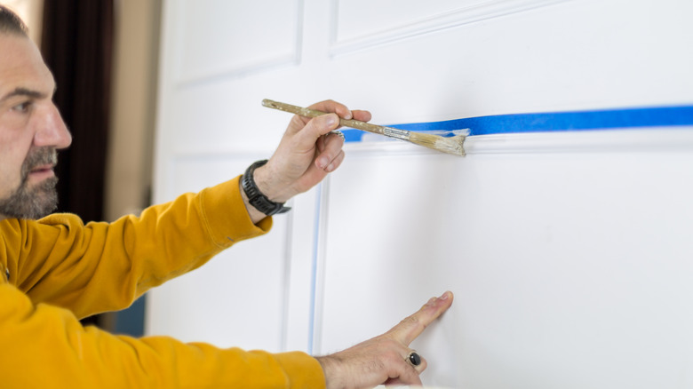 Person painting around painter's tape.