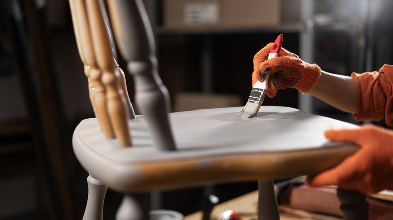 woman painting a wooden chair