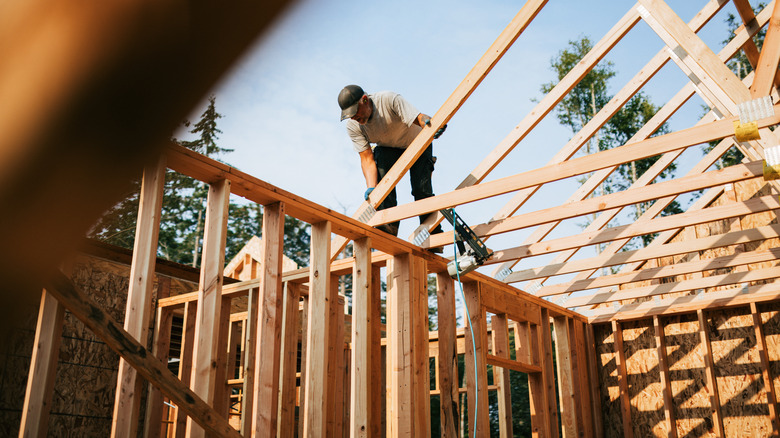 Man putting trusses on a roof, building a house
