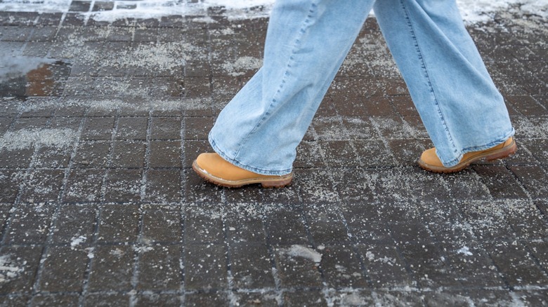 A person walking across a surface spread with anti-ice salt