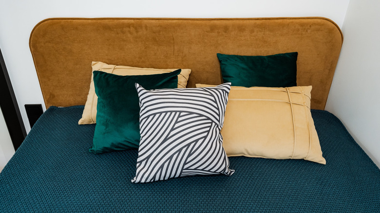 A rustic headboard with teal and tan accent pillows