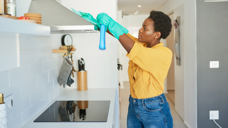young woman cleaning range in kitchen