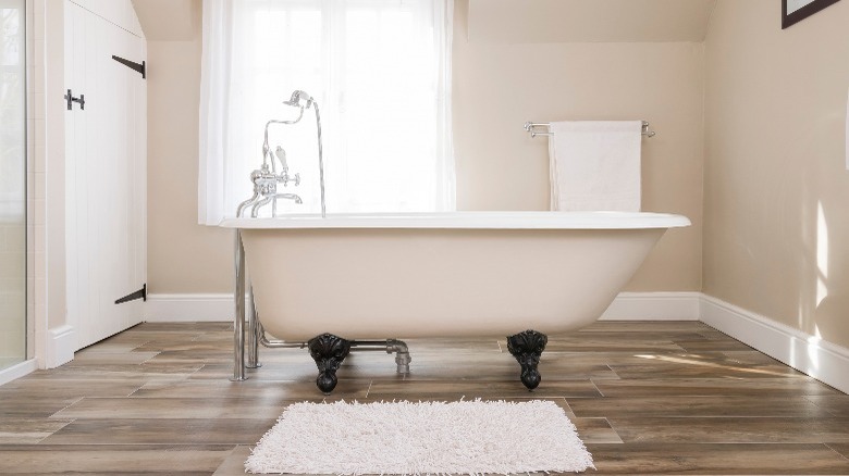bathroom with white curtains, towel, bath mat