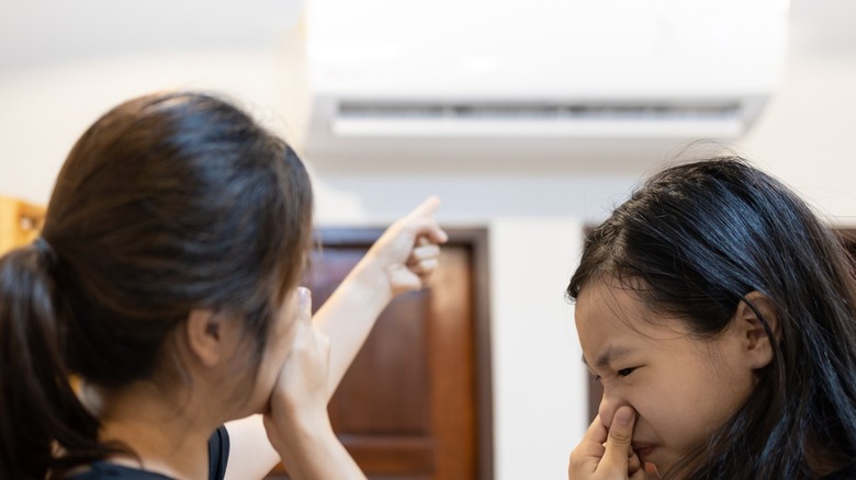 Two women holding noses and pointingn to vent