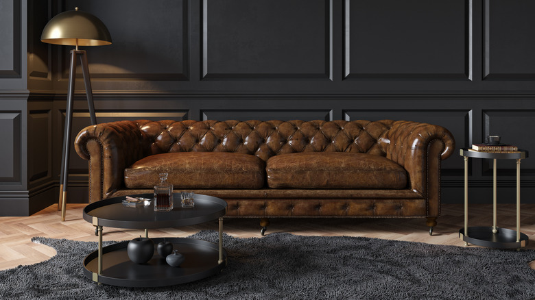 A Chesterfield sofa against a matte black wall