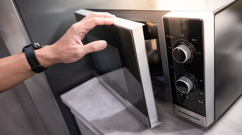 Person inspecting microwave at showroom