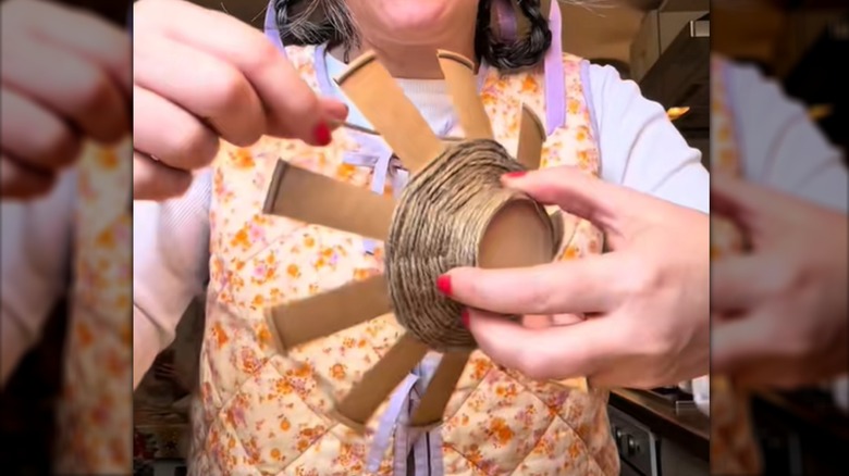 Person weaving twine around a slit paper cup