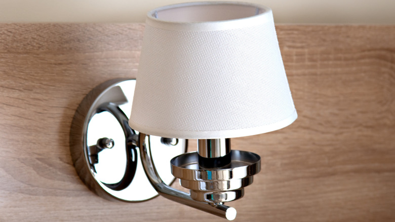 Basic white wall sconce mounted on a piece of wood