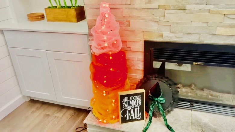 Tomato cage wrapped in three colors of fabric with lights to fresemble candy corn.