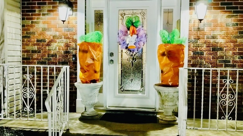 Giant carrots in planters flank the front door on this porch.