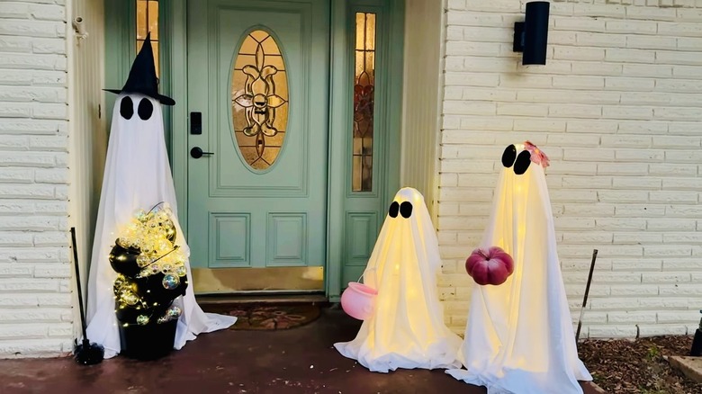 Three ghosts made from tomato cages and outfitted with lights.