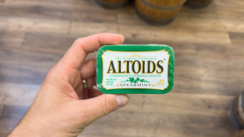 Hand holding a tin can of Altoids