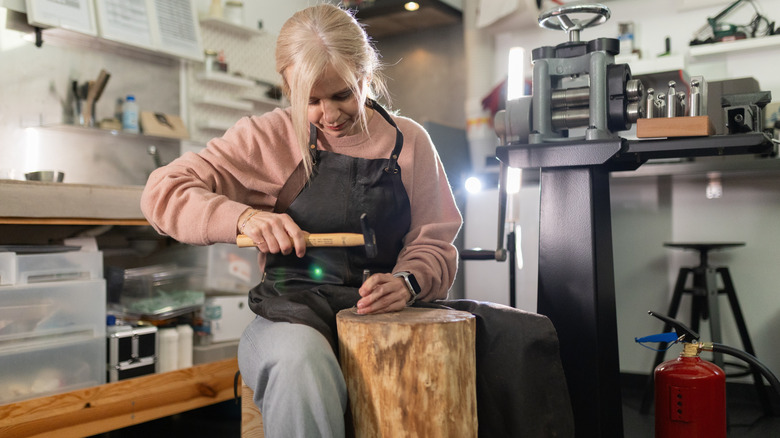 A woman crafting metal with a hammer in a workshop