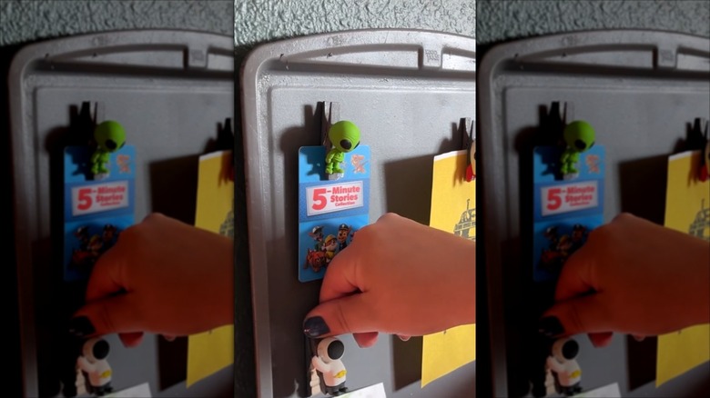 Hand putting clothespin magnets on a message board