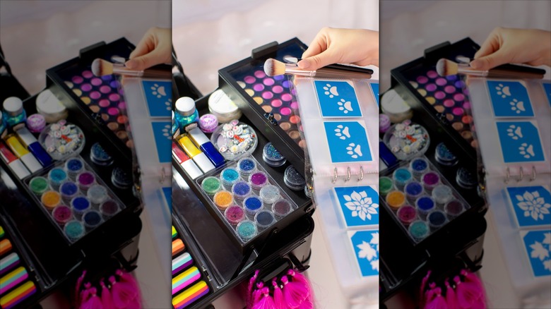 Hand holding a book of stencils and some paint