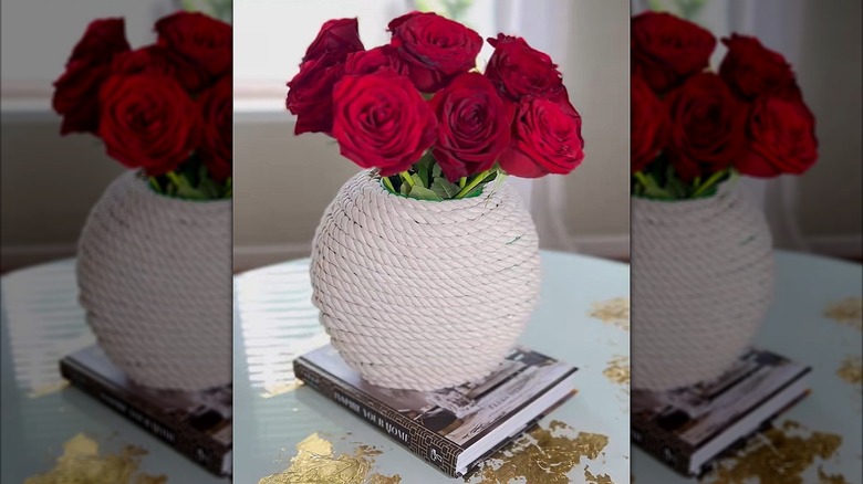 Red roses in a round vase covered in nautical rope.
