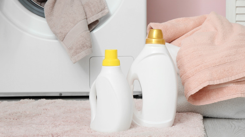 Two white laundry detergent bottles in front of a washer.