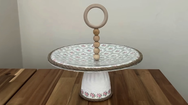 A DIY white  and floral kitchen storage stand made from an old pot lid and glass.