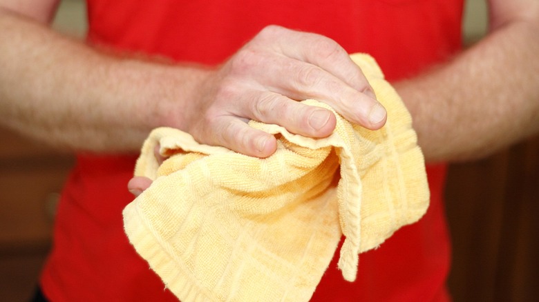 Close-up of a person drying their hands with a small yellow towel