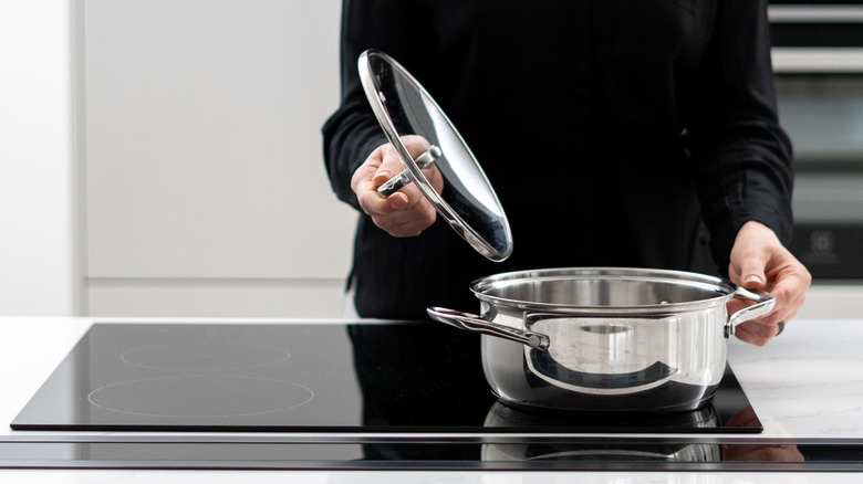 A woman opening the lid of an empty pot