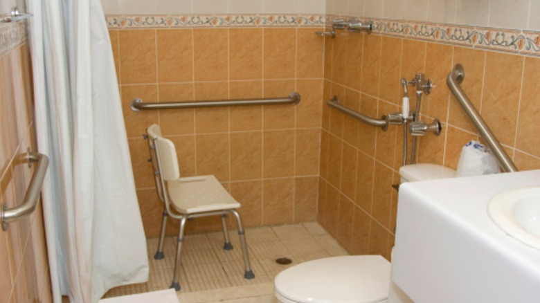 A bathroom for someone with mobility issues with several grab bars throughout and a shower chair.