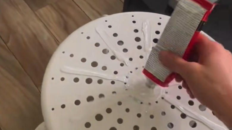 Person applying glue to a stool surface