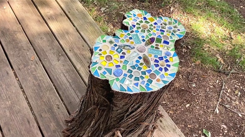 A pretty yellow and blue mosaic design laid on top of a cedar tree stump table.