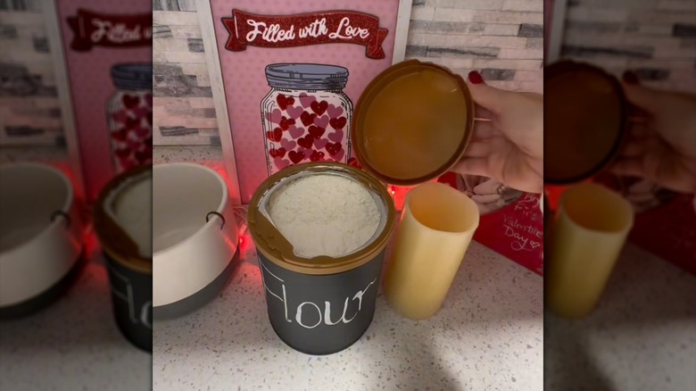 Woman's hand holding lid open to a baby formula container repurposed into flour bin.