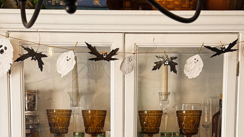 View of a cabinet strung with an adorable garland made of leaves painted white and black