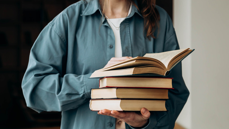 A person holds a stack of books