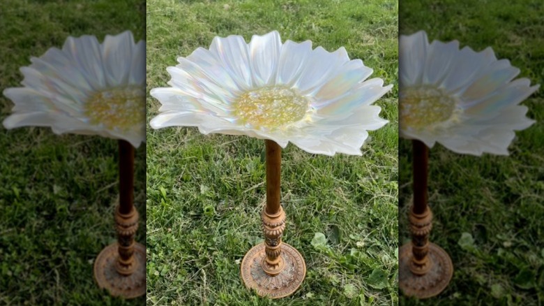 A bird bath made from a floor lamp stand and a flower-shaped glass platter.
