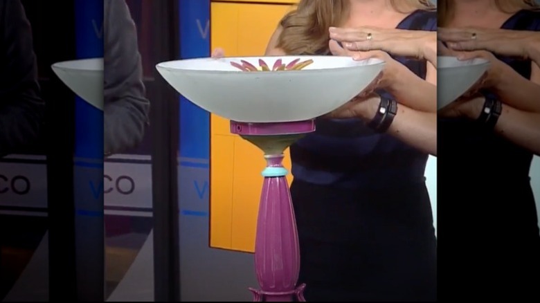 People assemble a bird bath using lots of different glass light fixtures.